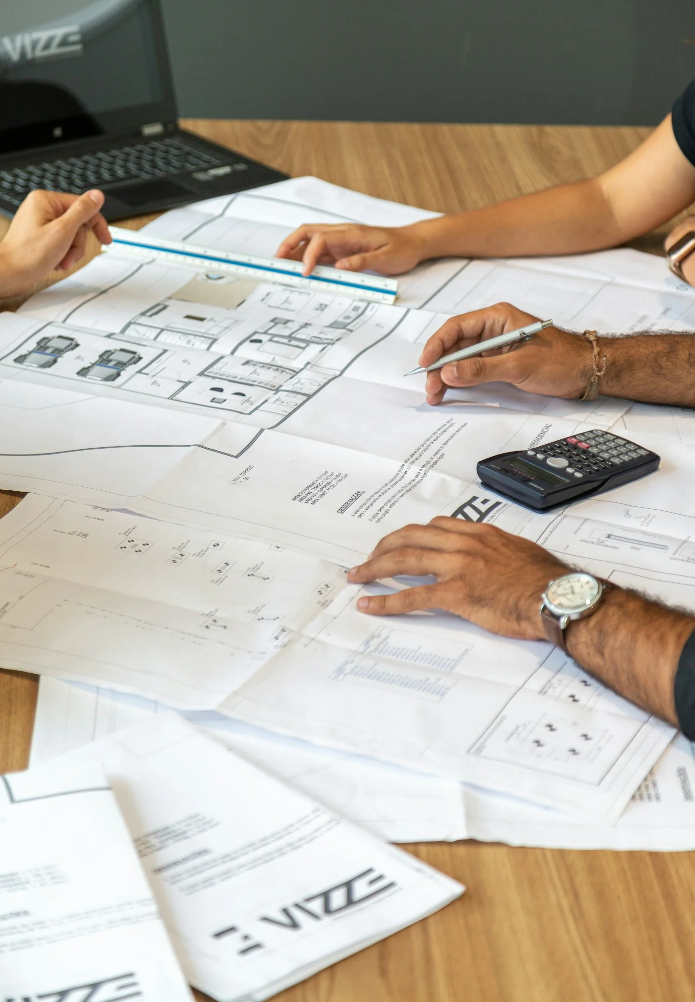 Profissionais analisando plantas de um projeto sobre a mesa